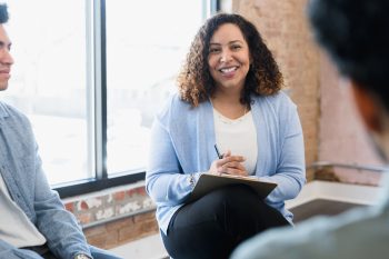 Female manager smiles at unrecognizable man seated across from her