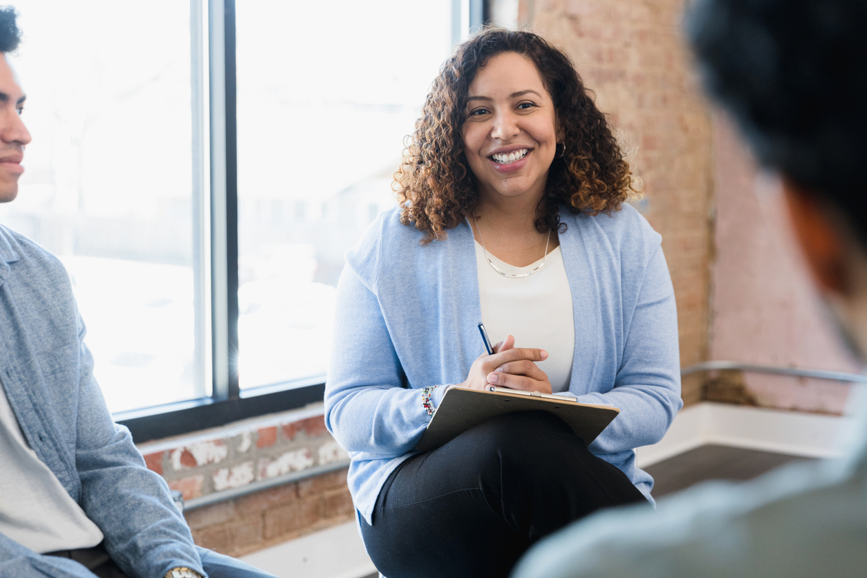 Female manager smiles at unrecognizable man seated across from her