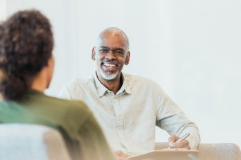 Unrecognizable client and male counselor share laugh
