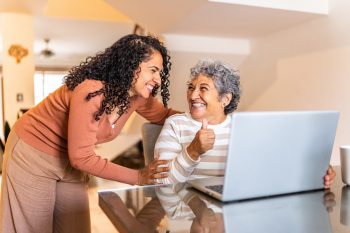 Senior woman using laptop and talking to daughter at home