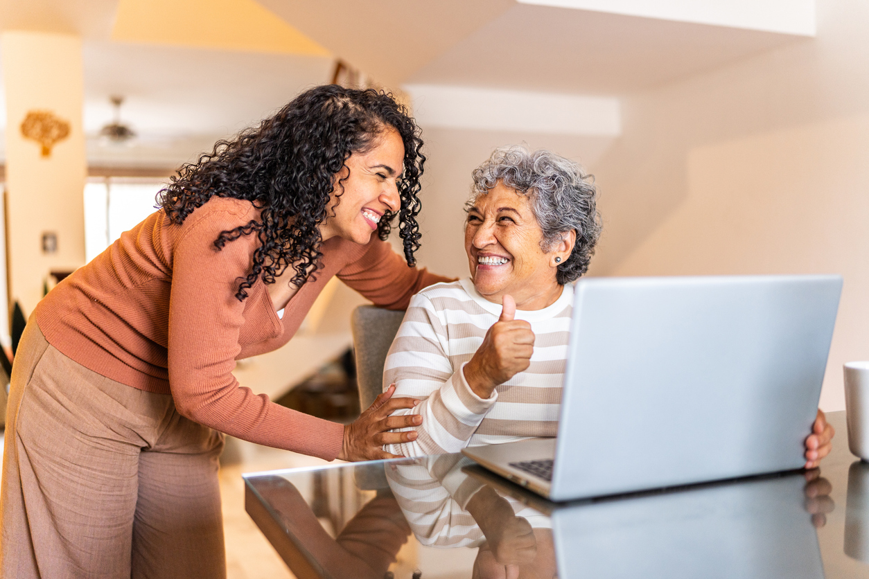 Senior woman using laptop and talking to daughter at home