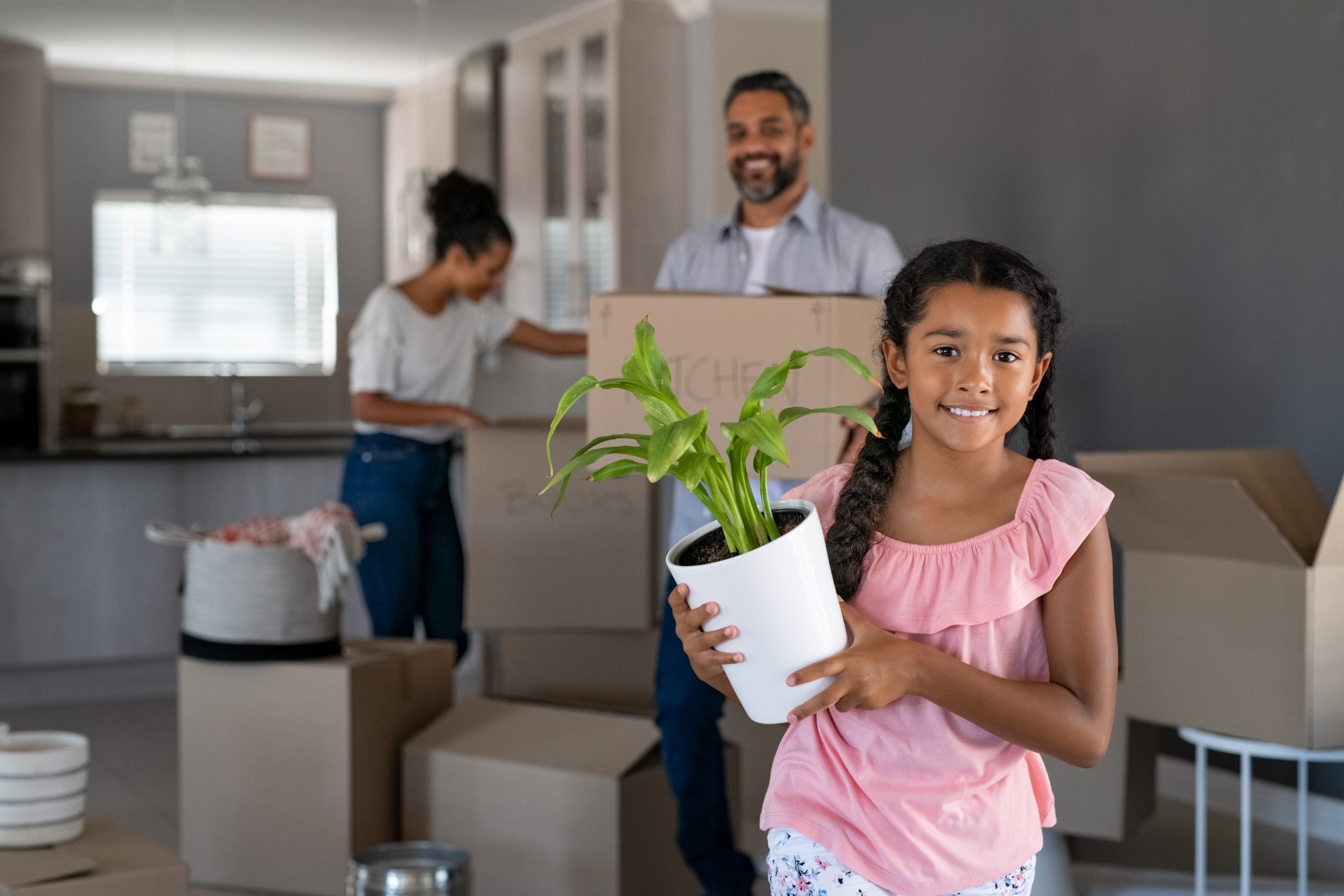 Smiling mixed race girl moving house with parents