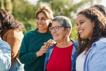 Group of multiracial women with different age meet each other at city park   Multi generational female circle outdoor   Focus on senior woman face